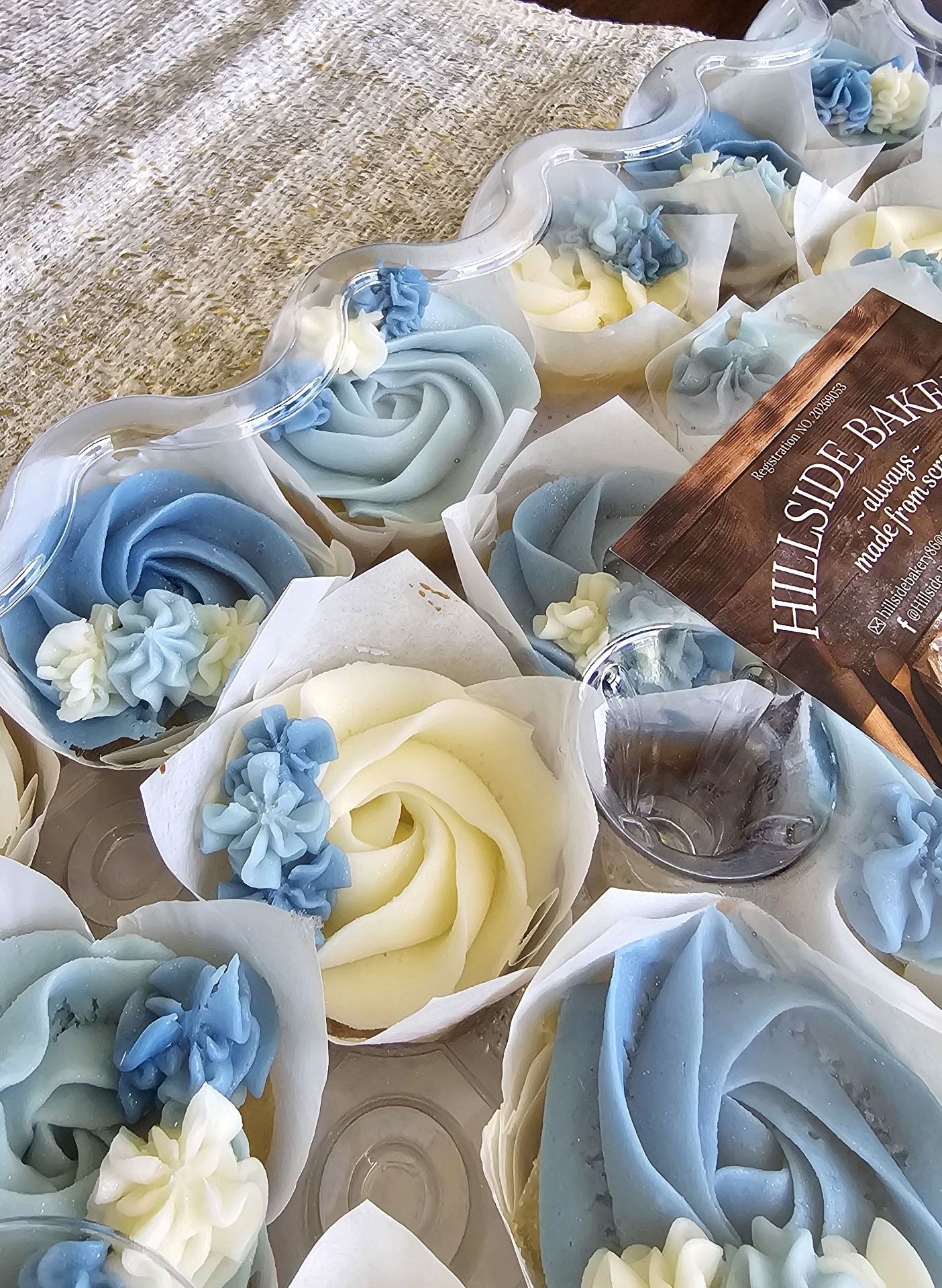Blue and cream buttercream rose cupcakes with Hillside Bakery card