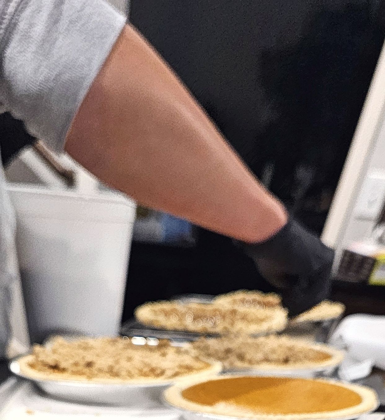 Assortment of streusel-topped and pumpkin pies being finished by hand