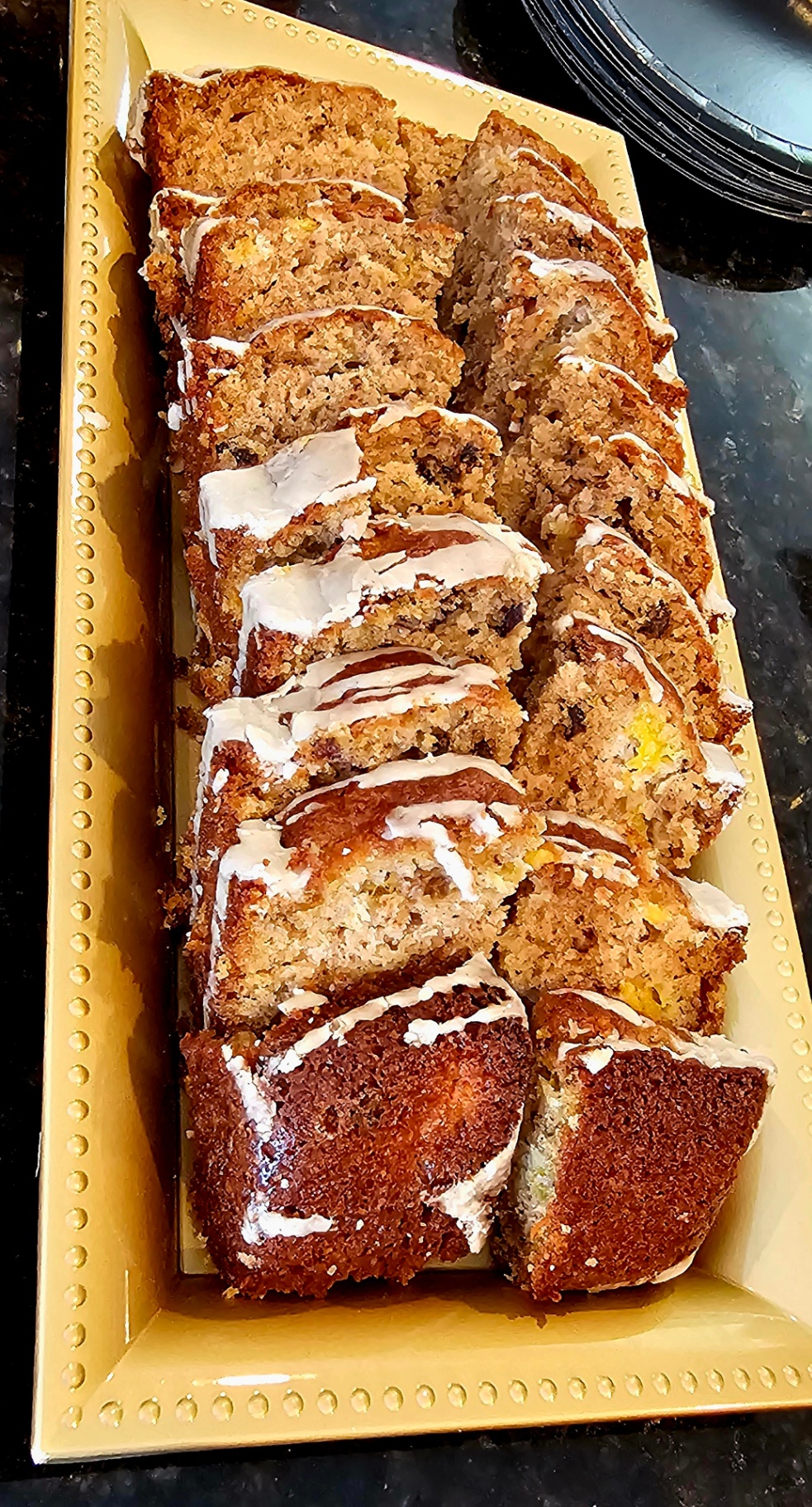 Sliced sweet bread drizzled with vanilla glaze on a yellow tray