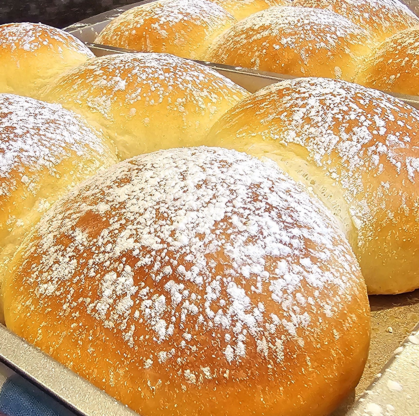 Golden brioche buns dusted with powdered sugar