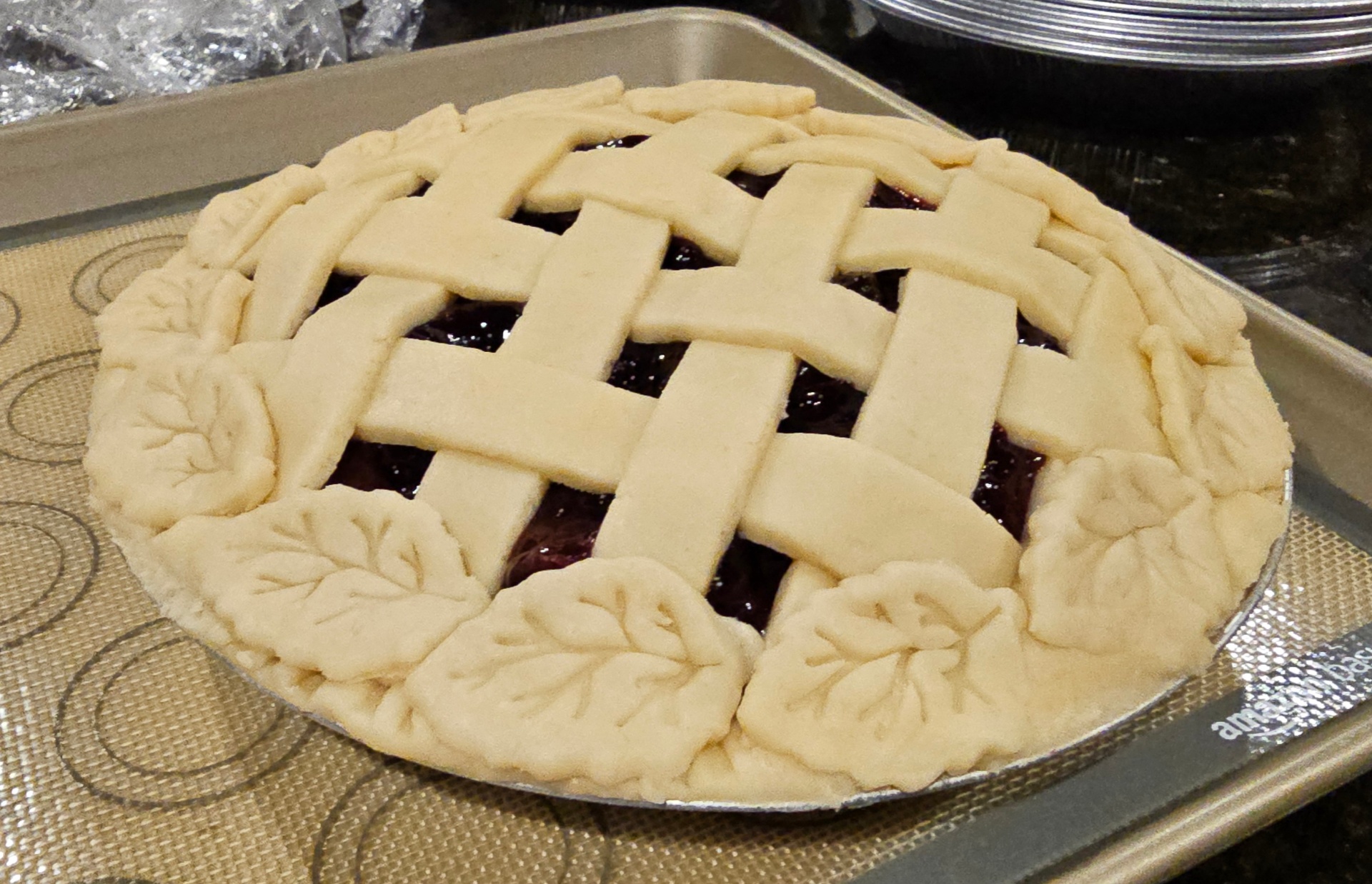 Unbaked berry pie with woven lattice top and hand-shaped pastry leaves